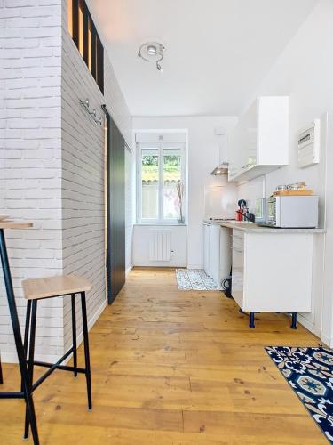 une cuisine avec des armoires blanches et un plancher en bois dans l'établissement Studio Loubet, à Cherbourg en Cotentin