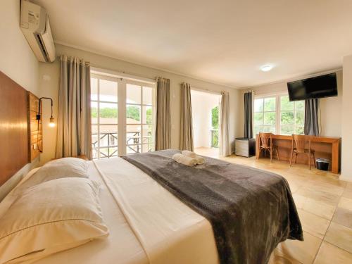 a bedroom with a large bed and a television at Resort La Marina in Búzios