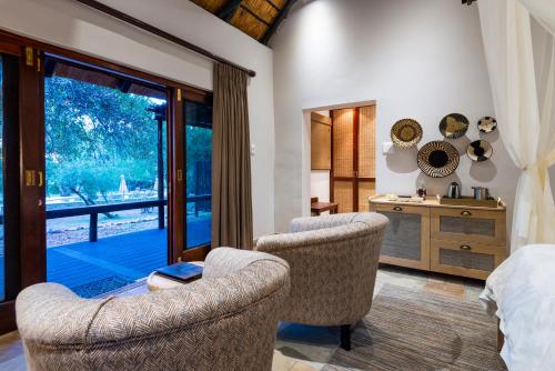 a bedroom with two chairs and a bed and a window at Inyati Game Lodge in Sabi Sand Game Reserve