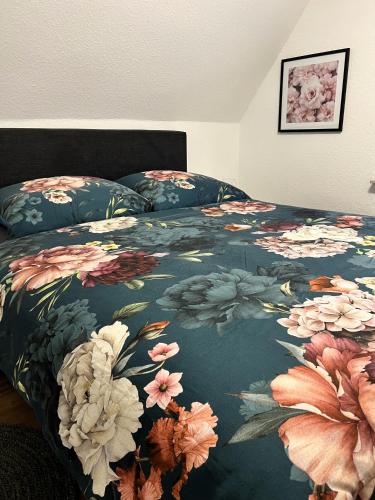 a bed with a floral comforter on top of it at FeWo Rehborn in Rehborn