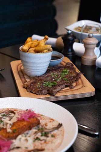 a table with a plate of food and a bowl of fries at FirstName Bordeaux, Part of JdV by Hyatt in Bordeaux
