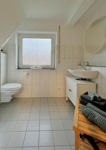 a bathroom with a sink and a toilet and a window at FeWo Rehborn in Rehborn