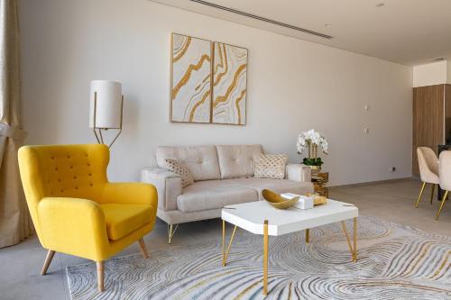 a living room with a yellow chair and a couch at Simply Comfort Vacation Homes Rental Modern 1Br in the Heart of Dubai in Dubai
