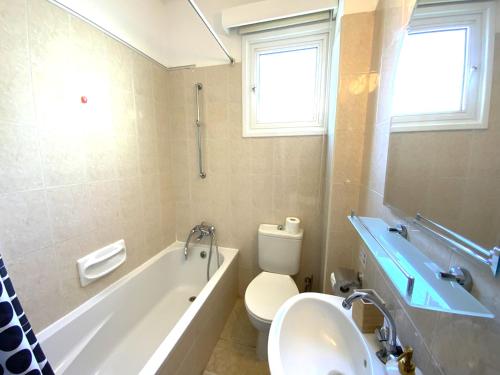 Un baño con bañera, inodoro y lavabo. en Cozy 2BR Beach Apt, Perfect for Getaways, en Lárnaca
