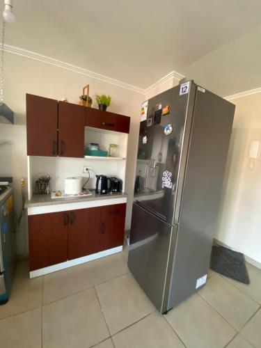a kitchen with a stainless steel refrigerator and wooden cabinets at Depto completo hasta 5 personas in Los Andes