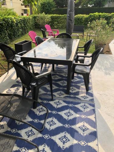 une table et des chaises en verre sur un tapis bleu et blanc dans l'établissement Villa les peupliers, à Royan