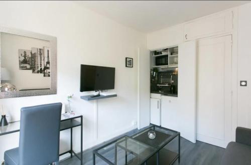 Elle comprend un salon avec un bureau et une télévision murale. dans l'établissement Appartement charmant proche Montparnasse, à Paris
