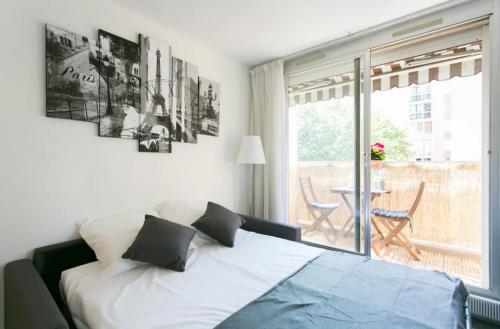 une chambre avec un lit et un balcon avec une table dans l'établissement Appartement charmant proche Montparnasse, à Paris