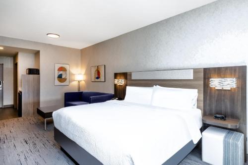 a hotel room with a bed and a blue chair at Holiday Inn Express and Suites Missoula by IHG in Missoula