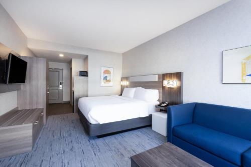 a hotel room with a bed and a blue couch at Holiday Inn Express and Suites Missoula by IHG in Missoula