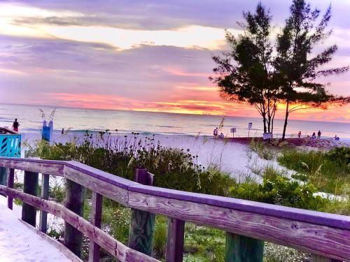 a wooden fence next to a beach with a tree at Amazing views & steps to beach 2B-2Bath-Pool 333 in Clearwater Beach
