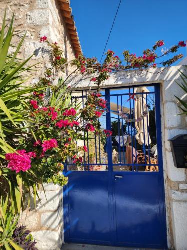 a blue door with flowers on a building at 85 sqm Apartments New Panorama ELECTRIC CAR ΦΩΡΤΗΣΗΣ STATION in Paralion astros