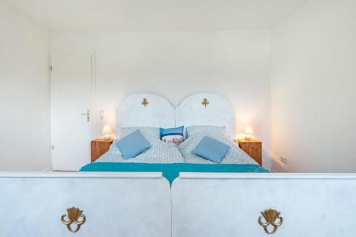 - une chambre blanche avec un lit et des oreillers bleus dans l'établissement Fewo Luv und Lee am Schulensee, à Molfsee