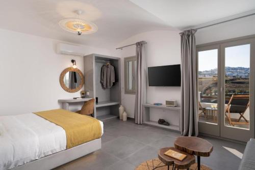 a bedroom with a bed and a tv and a balcony at Santa Mar ECO Suites in Karterados