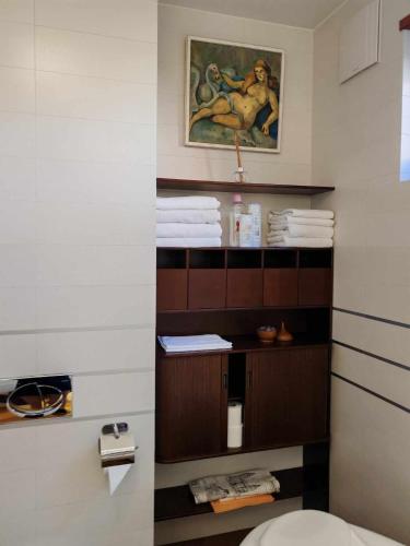 a bathroom with a toilet and a painting on the wall at Aquincum Dunaparti Apartman in Budapest