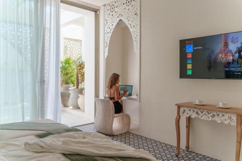 a woman sitting in a chair in a bedroom at Sana Tulum Beachfront Boutique Hotel in Tulum