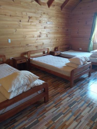 a room with three beds in a log cabin at Amanecer de Caburgua in Pucón