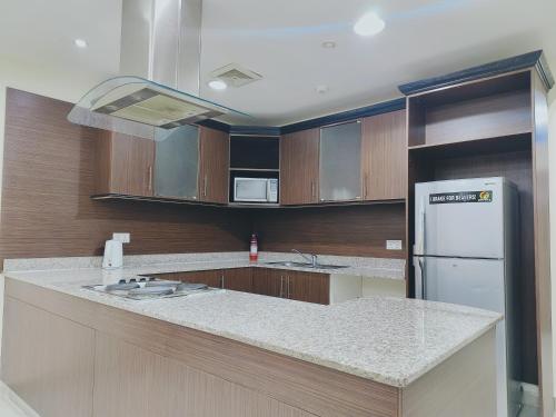 a kitchen with wooden cabinets and a white refrigerator at Marina Tower in Juffair