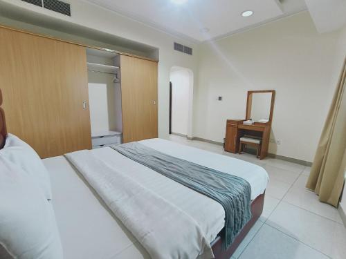 a bedroom with a bed and a dresser and a mirror at Marina Tower in Juffair