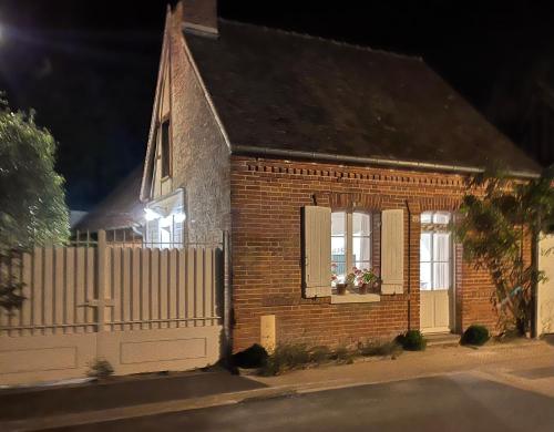 a brick house with a white fence and a window at La petite maison in Souvigny-en-Sologne