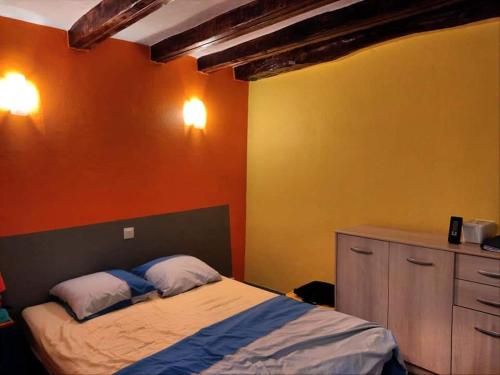 - une chambre avec un lit et un mur orange dans l'établissement LE NORD AU SUD de 3 à 6 personnes près Les Gorges du Verdon, à Villecroze
