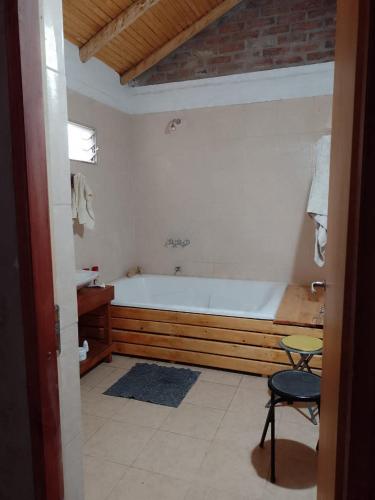 a bathroom with a tub and a table and a chair at Cabañas Zorzal Rodeo in Rodeo
