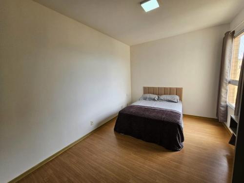 a bedroom with a bed and a wooden floor at Lindo AP com vista para a Lagoa dos Ingleses in Nova Lima