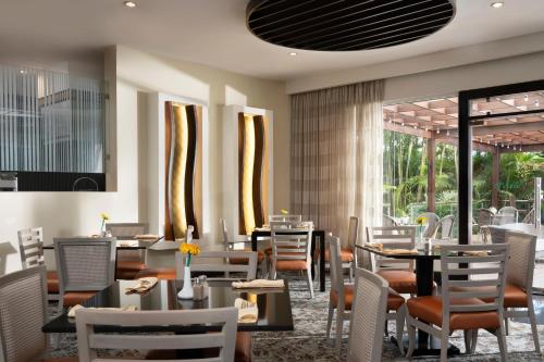 a dining room with tables and chairs and windows at Hodelpa Garden Court in Santiago de los Caballeros