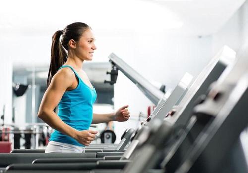 a woman running on a treadmill in a gym at Hodelpa Garden Court in Santiago de los Caballeros