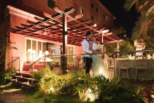 a man and woman standing outside of a restaurant at night at Hodelpa Garden Court in Santiago de los Caballeros