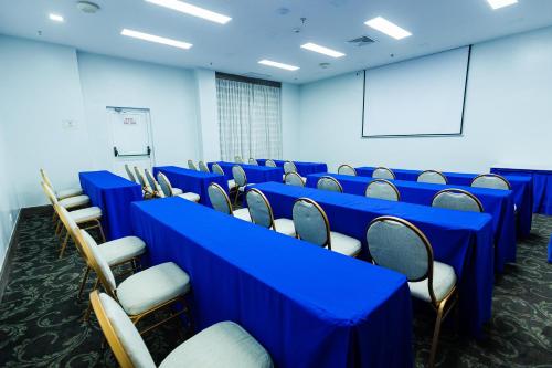 a conference room with blue tables and chairs at Hodelpa Garden Court in Santiago de los Caballeros