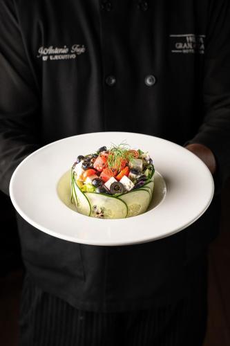 a man holding a plate with a salad on it at Hodelpa Gran Almirante in Santiago de los Caballeros