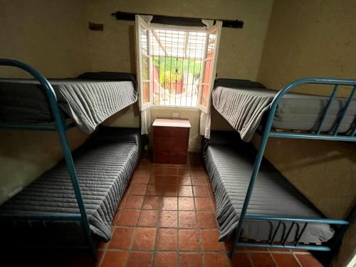 three bunk beds in a room with a window at Urban Salta Hostel in Salta