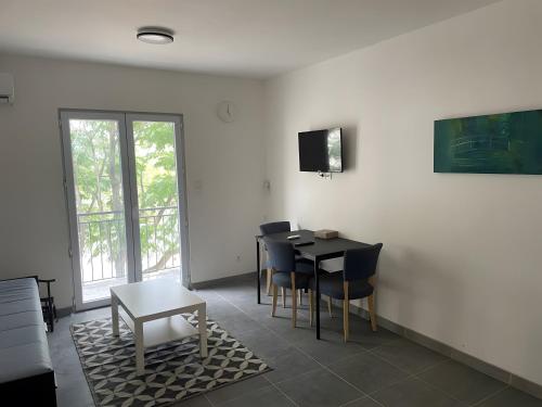 a dining room with a table and chairs and a tv at Appartement bord d'etang in Poussan