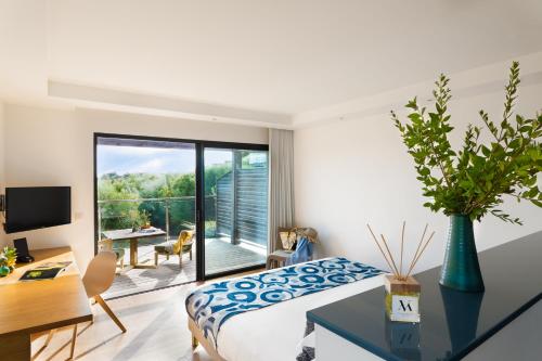 a bedroom with a king sized bed and a desk and a desk at Hôtel Version Maquis Santa Manza in Bonifacio