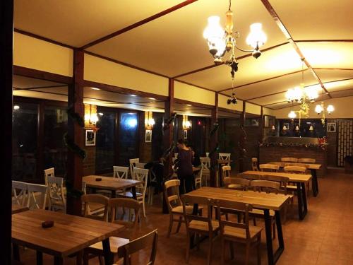 a restaurant with wooden tables and chairs and a person at Hotel Class in Brezoi