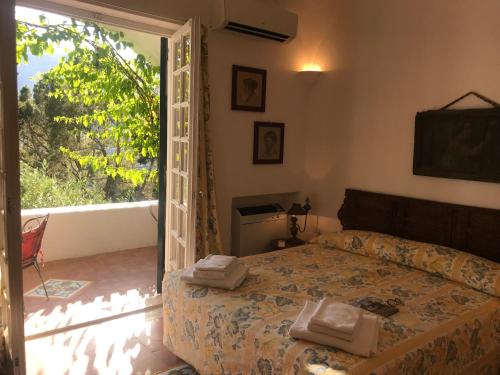 - une chambre avec un lit et une porte donnant sur un balcon dans l'établissement Villa Guya, à Capri