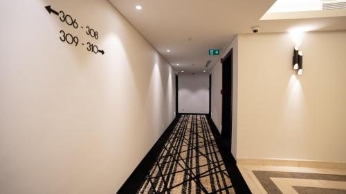 a hallway with a white wall with a black and white artwork at Mirada Blue Falestine - Serviced Apartments in Jeddah