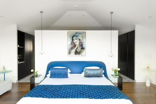 a bedroom with a blue bed and white walls at Hôtel Version Maquis Santa Manza in Bonifacio