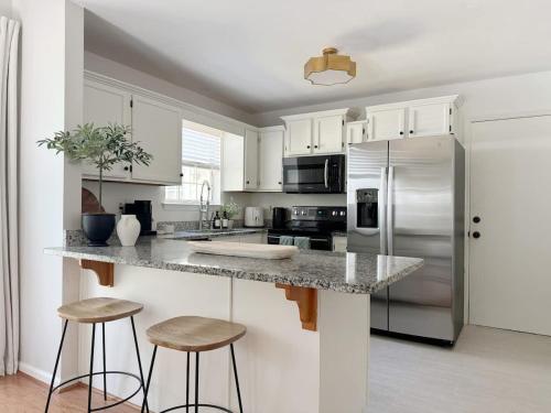 a kitchen with white cabinets and a counter with stools at Charming Cottage for Family and Dogs near Beach & City in Savannah