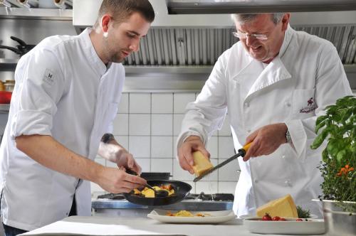 two chefs in a kitchen preparing food in a pan at Landgasthof Eiserner Ritter in Boppard