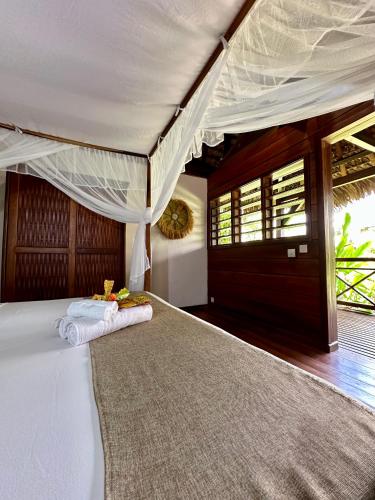 a bedroom with a white bed with a canopy at La Parenthèse in Nosy Be