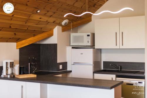 une cuisine avec des armoires blanches et un comptoir noir dans l'établissement Grand T4 confortable au pied des pistes pour 8 personnes, à Saint-Étienne-en-Dévoluy