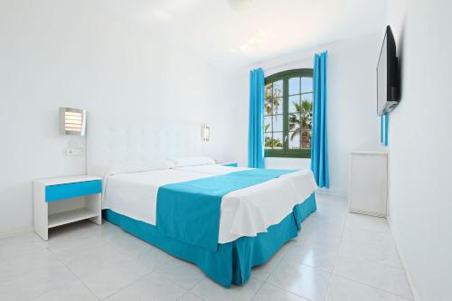 a white and blue bedroom with a bed and a tv at Hotel Moon Dreams Marina Parc in Na Macaret