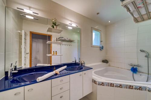 La salle de bains est pourvue d'une grande baignoire et d'un lavabo. dans l'établissement Villa Piscine Eau Salée avec jeux multiples, à Saint-Ismier