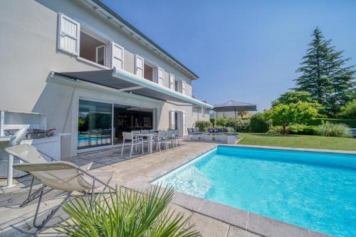 une maison avec une piscine devant une maison dans l'établissement Villa Piscine Eau Salée avec jeux multiples, à Saint-Ismier