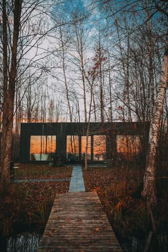 a wooden walkway leading to a building in the woods at Ezernams SPA in Kaukuri