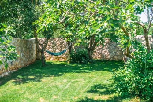 a hammock in a garden with a wall at VILLA CASTRA in Drivenik
