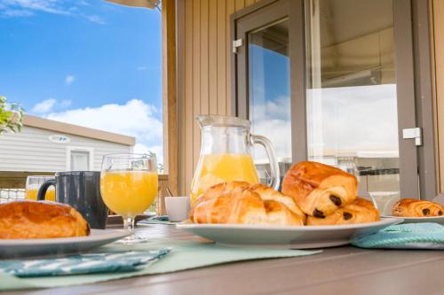 une table avec une assiette de pain et de jus d'orange dans l'établissement Mobil home Bord de Mer, à Fouesnant