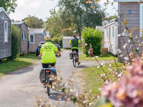 2 personnes font du vélo sur une route dans l'établissement Mobil home Bord de Mer, à Fouesnant